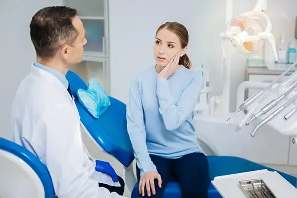 Woman touching cheek due to toothache at dental clinic
